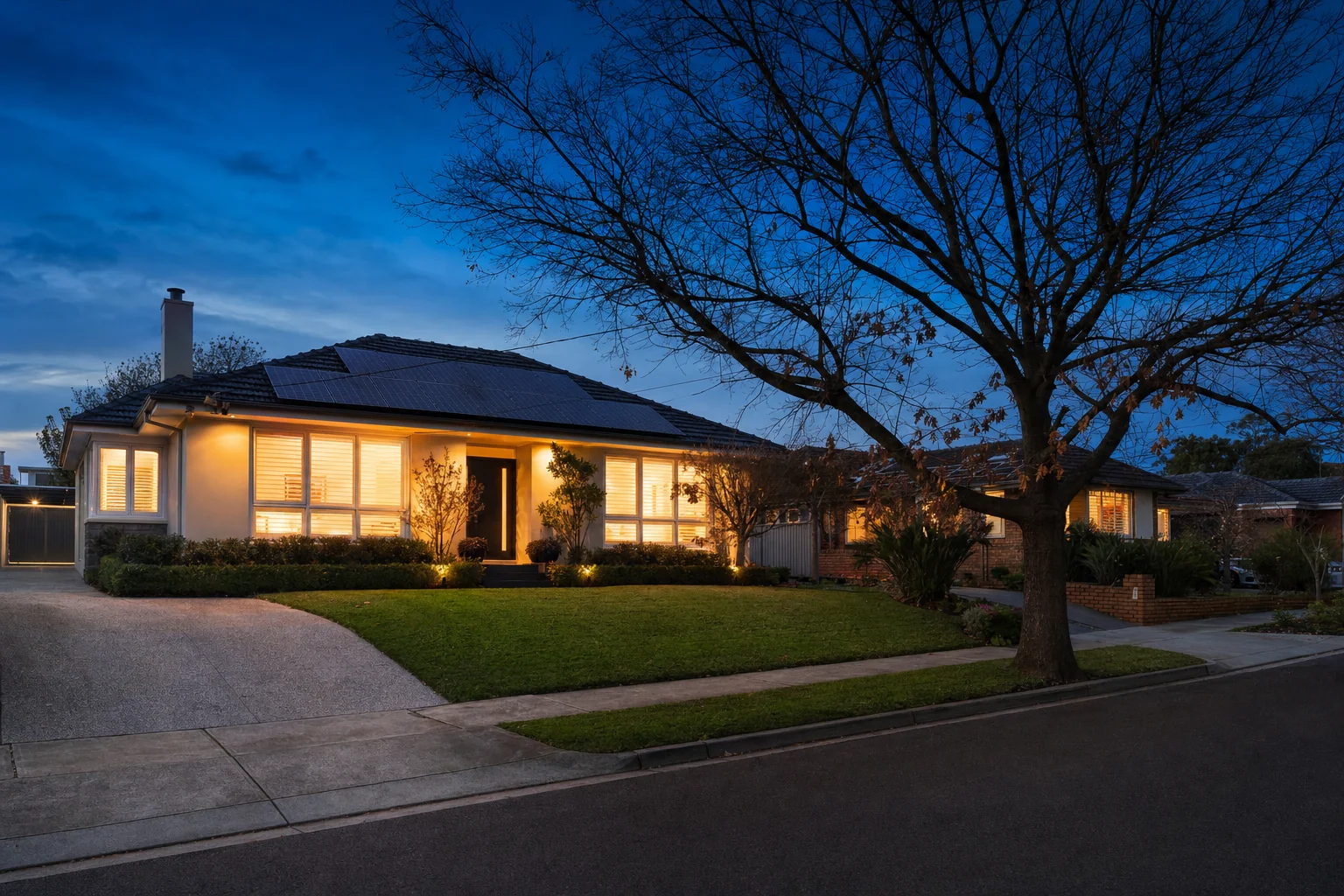 Melbourne suburban home at dusk with lights on inside, running the evening on stored solar power