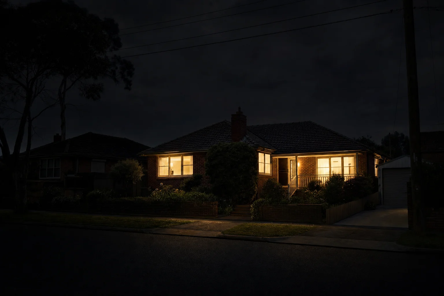 Melbourne suburban home at night with every room lit during a neighbourhood blackout, kept running by a whole-home battery backup system