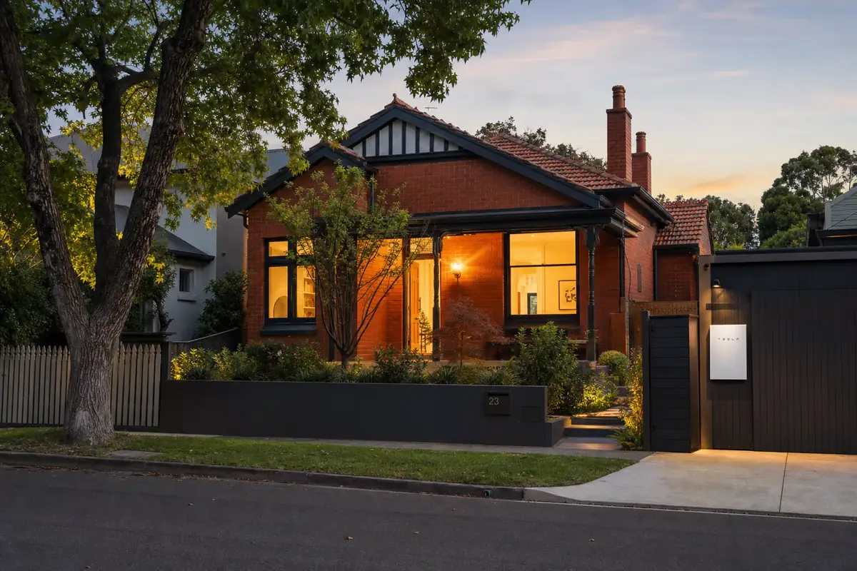 Melbourne home at dusk with warm interior lights on, powered by a wall-mounted home battery during a peak grid demand period