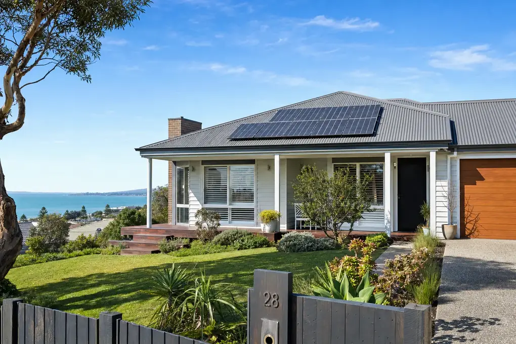 Solar battery system mounted on a Frankston home with rooftop solar panels and Port Phillip Bay backdrop