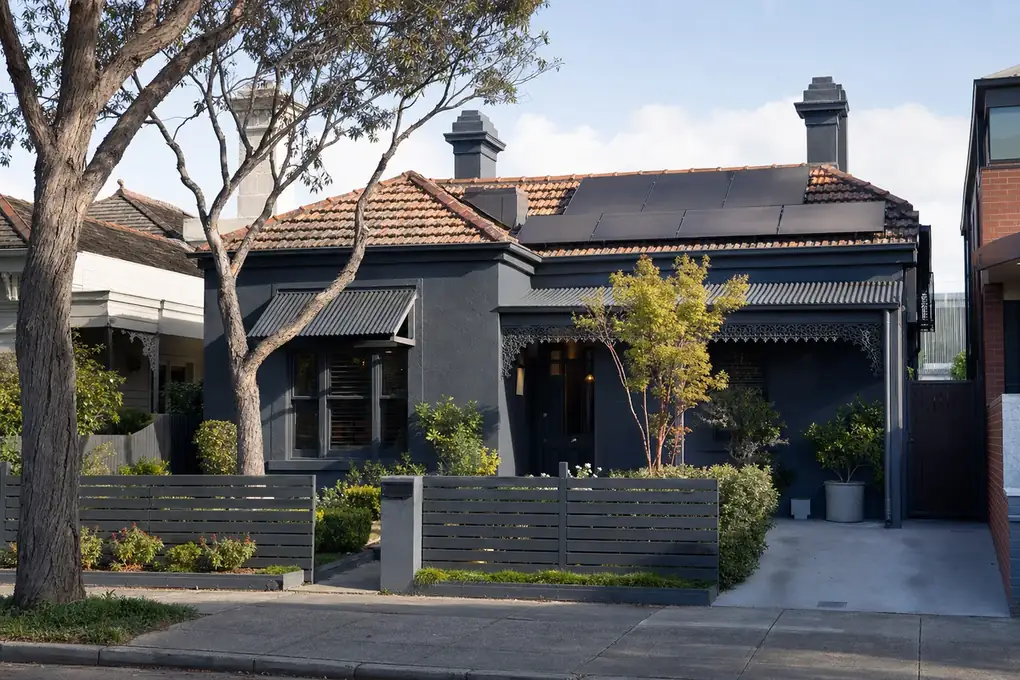 Home battery mounted on the side wall of a Williamstown Victorian heritage home, with a carefully integrated rooftop solar array and Port Phillip Bay in the background
